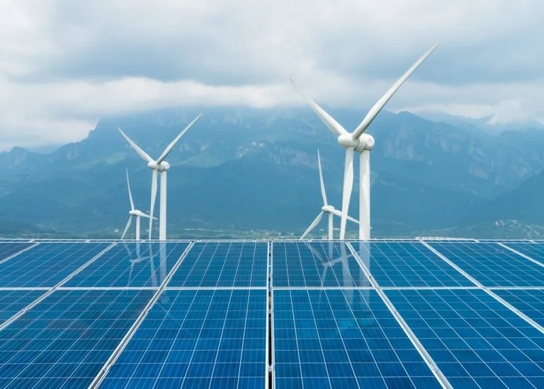 Conjunto de painéis solares e turbinas eólicas em um campo montanhoso, destacando as principais fontes de energia renováveis do mundo.