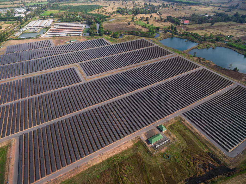 Imagem aérea de fazenda solar com diversos painéis gerando energia de forma sustentável.