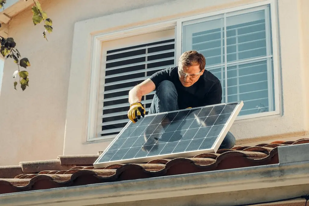 Homem instalando painel solar no telhado para economia de energia residencial