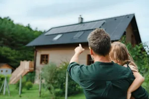 Família observando casa com sistema de energia solar residencial instalado no telhado