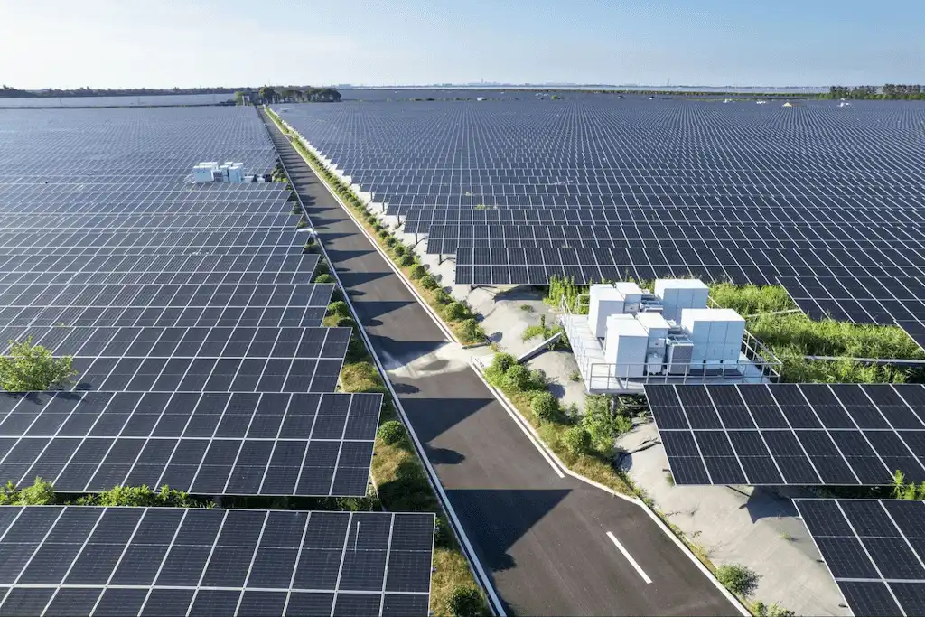 Vista aérea de uma grande usina solar com milhares de painéis fotovoltaicos, destacando as vantagens da energia solar limpa e sustentável.