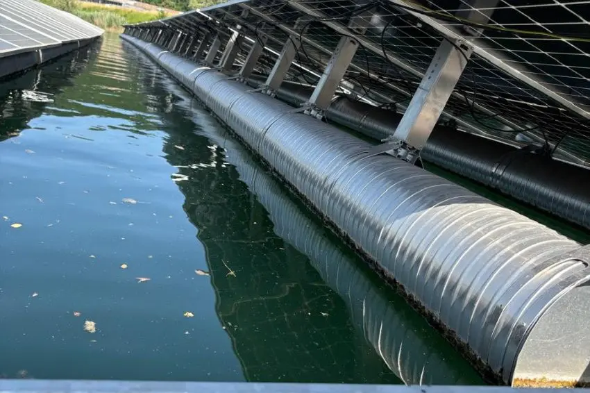 Estrutura em alumínio e catamarã patenteado Do ponto de vista técnico, a solução substitui os flutuadores plásticos convencionais por uma estrutura em alumínio naval, material que oferece maior resistência mecânica, durabilidade e estabilidade ao longo do tempo, além de ser não inflamável, resistente à radiação UV e 100% reciclável. O sistema adota flutuadores em formato de catamarã com tecnologia patenteada, contribuindo para maior estabilidade da planta e melhor distribuição de carga na lâmina d’água. O desenho estrutural também amplia a modularidade, permitindo adaptação a diferentes configurações de projeto. Outro diferencial está na inclinação dos módulos. Enquanto o padrão de mercado para sistemas flutuantes varia entre 8° e 10°, a solução permite instalação com até 15°, aumentando a captação de irradiância e, consequentemente, a geração de energia. A solução utiliza menor quantidade de material em comparação aos sistemas tradicionais de plástico, mantendo desempenho estrutural e operacional. Segundo as empresas, o custo se mantém compatível com tecnologias disponíveis no mercado, com ganhos adicionais em eficiência, logística e operação. Operação e manutenção simplificadas No campo operacional, a estrutura foi projetada para facilitar as atividades de operação e manutenção. O acesso aos módulos pode ser feito por ambos os lados, reduzindo o tempo de intervenção e minimizando impactos na geração. O sistema incorpora uma passarela técnica com eletrocalhas embutidas, responsável pela organização dos cabos e integração dos equipamentos elétricos. Esse layout permite a instalação dos inversores próximos às strings e garante acesso direto aos conectores dos módulos. Outro ponto é o uso de embarcações leves para manutenção, facilitando o deslocamento dentro da usina e reduzindo custos operacionais ao longo do tempo. Aplicações e desempenho internacional A solução foi desenvolvida para atender demandas tanto do setor elétrico quanto do agronegócio, incluindo aplicações como geração para sistemas de irrigação e aproveitamento de áreas hídricas ociosas. Projetos internacionais já validaram o desempenho da tecnologia. Em usinas implantadas em países europeus, foram registrados incrementos de 5% a 7% na geração energética, acompanhados por redução dos custos de operação e manutenção. Solução para usinas flutuantes incorpora “minifábrica” e produção de 1 MWp por semana